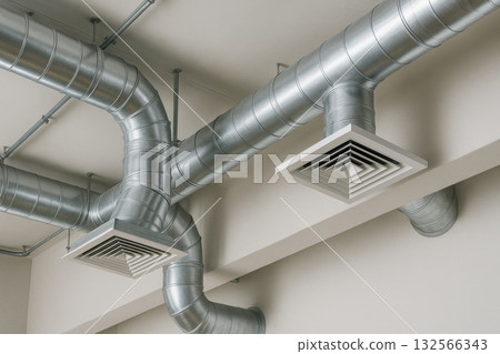 Modern HVAC system with indoor ceiling ventilation ducts made of shiny aluminum. This industrial air system connects to exhaust and return vents for building architecture Modern HVAC system with indoor ceiling ventilation ducts made of shiny aluminum. This industrial air system connects to exhaust and return vents for building architecture 132566343