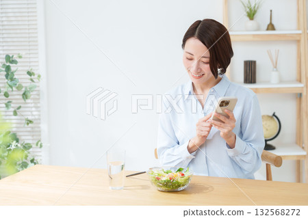Woman eating salad and smartphone Woman eating salad and smartphone 132568272