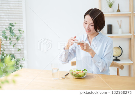 Woman eating salad and smartphone Woman eating salad and smartphone 132568275