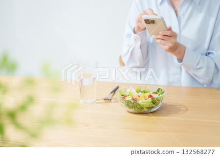 女人一邊吃沙拉一邊看手機 132568277