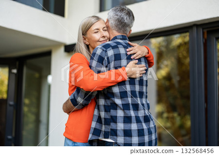 Long-haired woman in orange shirt hugging her husband Long-haired woman in orange shirt hugging her husband 132568456