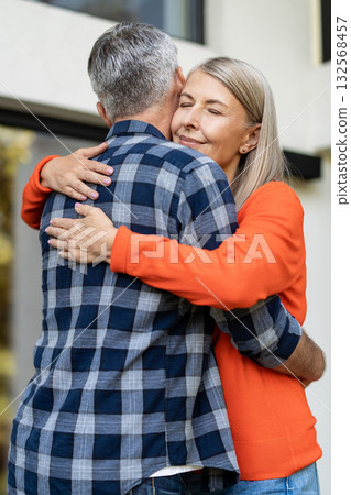 Long-haired woman in orange shirt hugging her husband 132568457