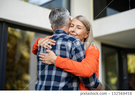 Long-haired woman in orange shirt hugging her husband Long-haired woman in orange shirt hugging her husband 132568458