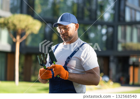 Male landscaper posing outdoors with gardening equipment in hands Male landscaper posing outdoors with gardening equipment in hands 132568540