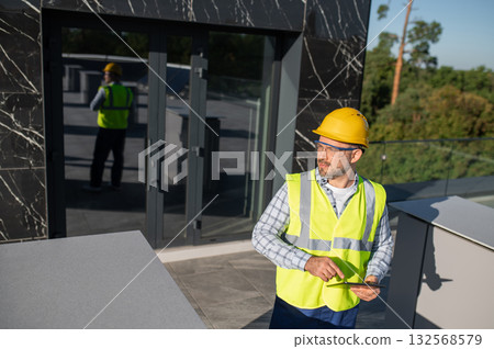 Professional worker assessing building with digital tool Professional worker assessing building with digital tool 132568579