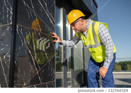 Technician checking construction details on building facade Technician checking construction details on building facade 132568589