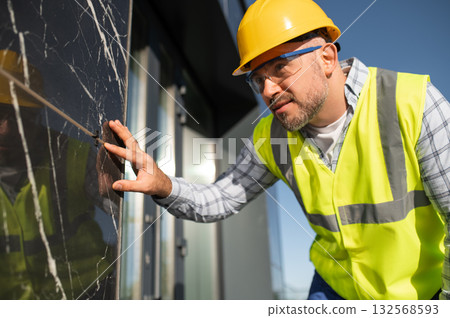 Worker examining exterior wall surface for quality and finish Worker examining exterior wall surface for quality and finish 132568593