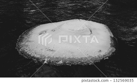 A serene winter scene of a frozen section of the Jizerka River. The icy surface contrasts with the flowing water, showcasing nature's beauty during cold months in the Czech landscape. A serene winter scene of a frozen section of the Jizerka River. The icy surface contrasts with the flowing water, showcasing nature's beauty during cold months in the Czech landscape. 132569035