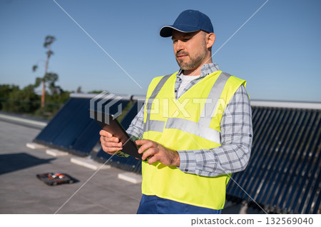 Engineer analyzing solar performance data on tablet near panels Engineer analyzing solar performance data on tablet near panels 132569040
