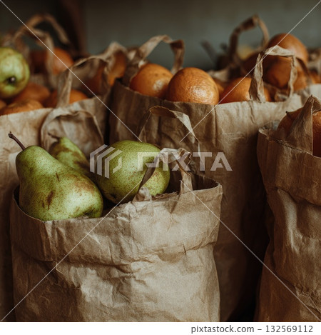 Fresh pears and oranges in paper bags arranged in a rustic setting with warm lighting and textures 132569112