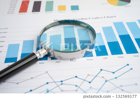Magnifying glass on spreadsheet and graph paper. 132569177