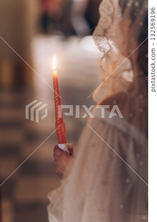 Burning wedding candle in bride's hands during Orthodox ceremony Burning wedding candle in bride's hands during Orthodox ceremony 132569196