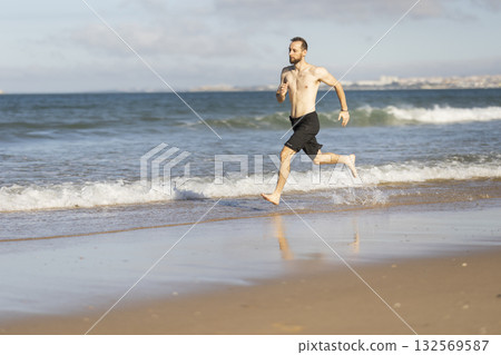 Barefoot man running on ocean beach exercising Barefoot man running on ocean beach exercising 132569587