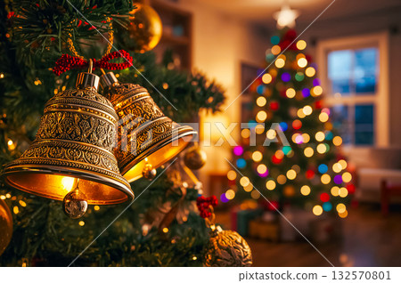 Closeup of gloden Christmas bells and illuminated Christmas tree. 132570801