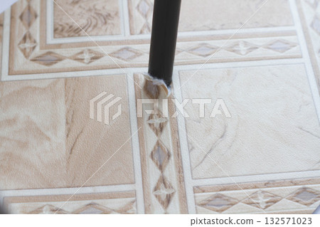 Ripped linoleum. Chair leg and torn linoleum. Hole in linoleum. 132571023