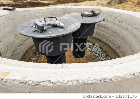 Two underground storage tanks are visible at a construction site in a rural area, with tools resting on top, ready for installation and maintenance 132571170