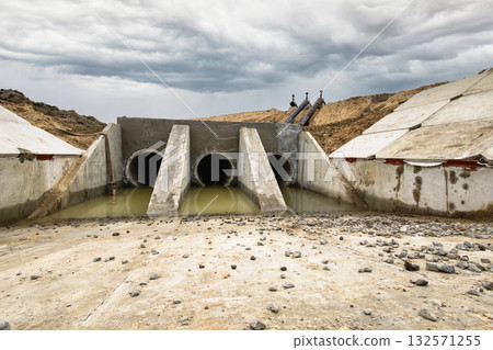 Construction workers develop a stormwater drainage system at a rural site. Heavy machinery is used while cloudy skies appear overhead, indicating possible rain Construction workers develop a stormwater drainage system at a rural site. Heavy machinery is used while cloudy skies appear overhead, indicating possible rain 132571255