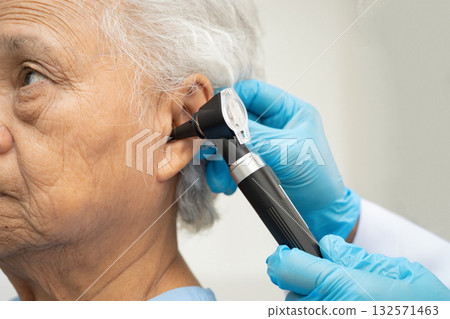 Otolaryngologist or ENT physician doctor examining senior patient ear with otoscope, hearing loss problem. Otolaryngologist or ENT physician doctor examining senior patient ear with otoscope, hearing loss problem. 132571463