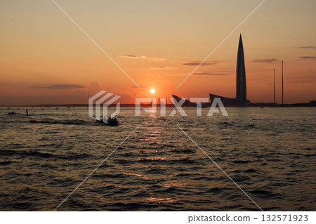 A breathtakingly stunning sunset over the water alongside a magnificent city skyline A breathtakingly stunning sunset over the water alongside a magnificent city skyline 132571923