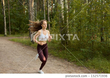 A Woman Running Enthusiastically in the Beautiful Nature Embracing Fitness and a Healthy Lifestyle 132571936