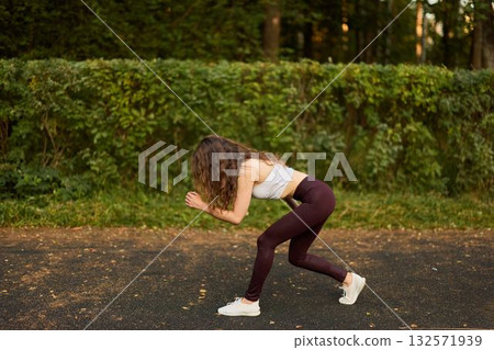 A woman is actively exercising outdoors while wearing trendy and stylish activewear attire 132571939