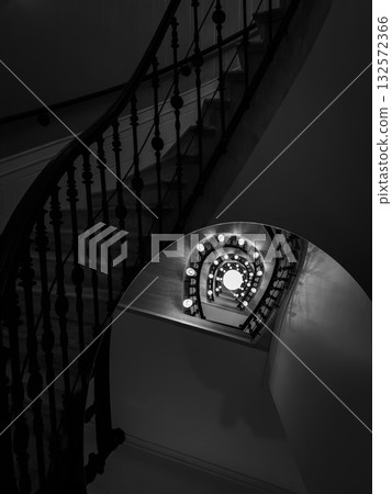 Spiral staircase in black and white with glowing circular railing lights creating depth Spiral staircase in black and white with glowing circular railing lights creating depth 132572366