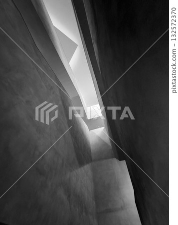 Abstract black and white architectural atrium with light beams through angled walls Abstract black and white architectural atrium with light beams through angled walls 132572370