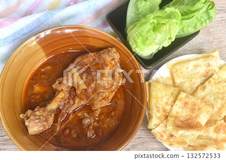 chicken leg massaman curry eat cuople with slice crispy roti and baby cos lecctue on bowl chicken leg massaman curry eat cuople with slice crispy roti and baby cos lecctue on bowl 132572533