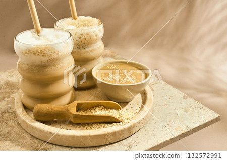 Sesame Tahini Latte Delight. Creamy sesame paste and iced tahini lattes on rustic travertine surface. 132572991