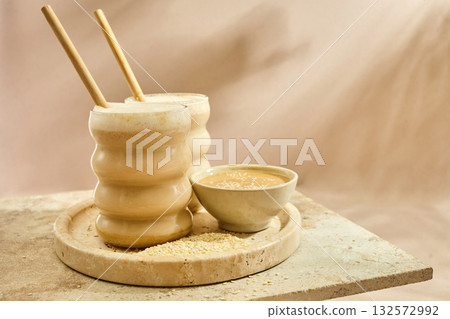 Sesame Tahini Latte Delight. Creamy sesame paste and iced tahini lattes on rustic travertine surface. Sesame Tahini Latte Delight. Creamy sesame paste and iced tahini lattes on rustic travertine surface. 132572992