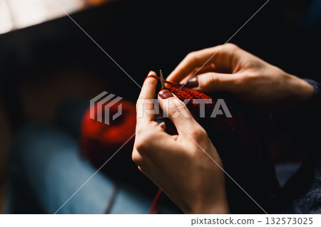Cozy Knitting Session With Red Yarn: Hands Crafting A Warm Scarf For Relaxation And Home Comfort 132573025