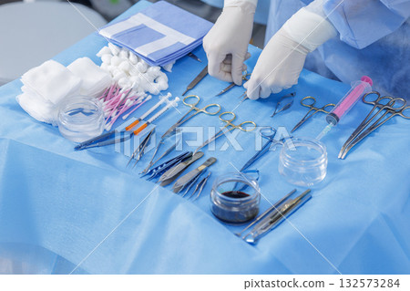 Gloved clinician organizes ophthalmic and facial plastic surgery tools on a sterile field for eyelid microsurgery preparation Gloved clinician organizes ophthalmic and facial plastic surgery tools on a sterile field for eyelid microsurgery preparation 132573284