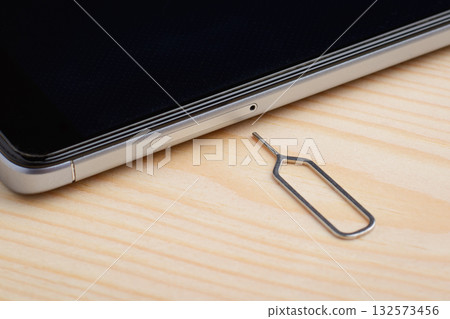 Clip for removing SIM card tray near modern mobile phone on light background 132573456