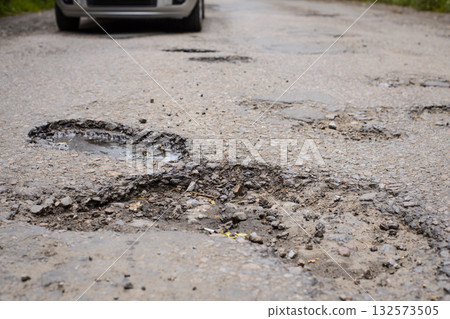 Many enormous potholes in asphalt surface. Concept of bad road, problems with road pavement 132573505