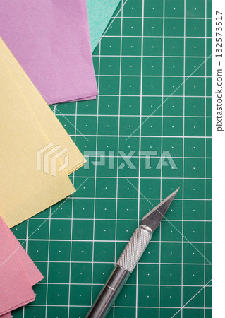 Cutting papers of different colour on a green cutting mat 132573517