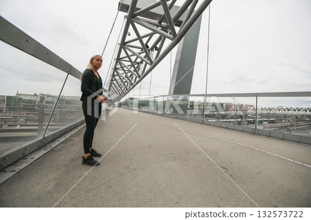 Woman standing on modern urban bridge with glass and metal structures 132573722