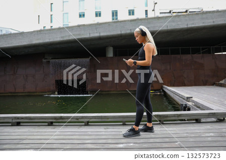 Woman exercising outdoors near modern architecture and urban waterfall Woman exercising outdoors near modern architecture and urban waterfall 132573723