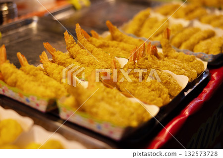 Golden fried shrimps arranged for display in a vibrant street food market Golden fried shrimps arranged for display in a vibrant street food market 132573728