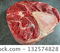 Side view of a raw beef shank steak with visible bone, placed on a dark stone countertop. High-resolution image with juicy texture, perfect for recipes, food blogs, packaging and culinary stock. 132574828