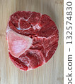 Close-up of raw beef shank cross-cut with visible bone, placed on a wooden cutting board. High-resolution image showing meat texture, perfect for cooking, culinary blogs and food stock use. 132574830