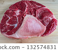 Close-up of raw beef shank cross-cut with visible bone, placed on a wooden cutting board. High-resolution image showing meat texture, perfect for cooking, culinary blogs and food stock use. 132574831