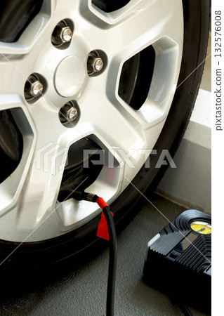 Car tire being inflated with portable air compressor and pressure gauge. Auto service and safety concept. 132576008