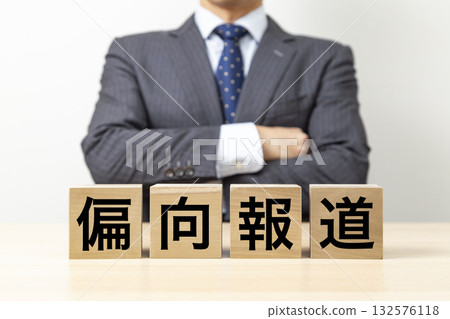 A businessman with his arms crossed and a block that reads "Biased Reporting" A businessman with his arms crossed and a block that reads "Biased Reporting" 132576118