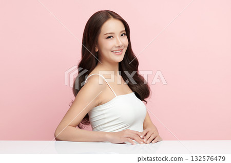 A beautiful young Asian woman with clean, fresh skin against a pink background. Skincare, facial treatment, cosmetology, beauty, and spa. An elegant portrait of an Asian woman. 132576479