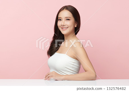A beautiful young Asian woman with clean, fresh skin against a pink background. Skincare, facial treatment, cosmetology, beauty, and spa. An elegant portrait of an Asian woman. 132576482