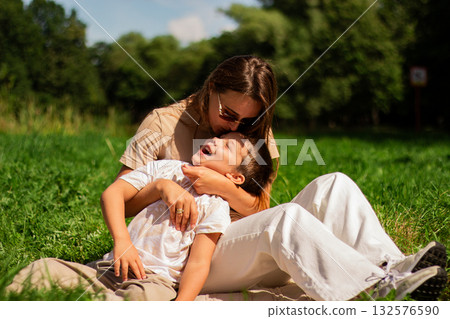 Portrait of young Caucasian single mother hugging her cute small son outside in park sending time on summer day together. Motherhood concept. 132576590