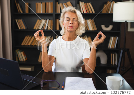 Yoga mindfulness meditation No stress keep calm. Middle aged woman practicing yoga at office. Woman taking break from work meditating relaxing. Mature lady doing breathing practice online yoga at work Yoga mindfulness meditation No stress keep calm. Middle aged woman practicing yoga at office. Woman taking break from work meditating relaxing. Mature lady doing breathing practice online yoga at work 132576772