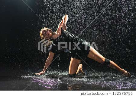 Contemporary woman dancer posing in rain water on black background. Female artist performer dancing with expression. Modern ballerina dancing in darkness. Passion dance in dark. Flexibility balance 132576795