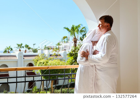 A romantic couple in white robes on a hotel terrace overlooking the garden A romantic couple in white robes on a hotel terrace overlooking the garden 132577264
