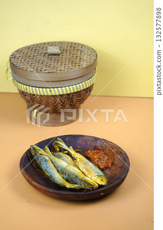 Fried milkfish with sambal, traditional Indonesian culinary dish, served on a wooden plate. 132577898